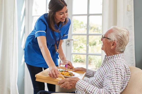 Home Care Caregiver providing meal to senior